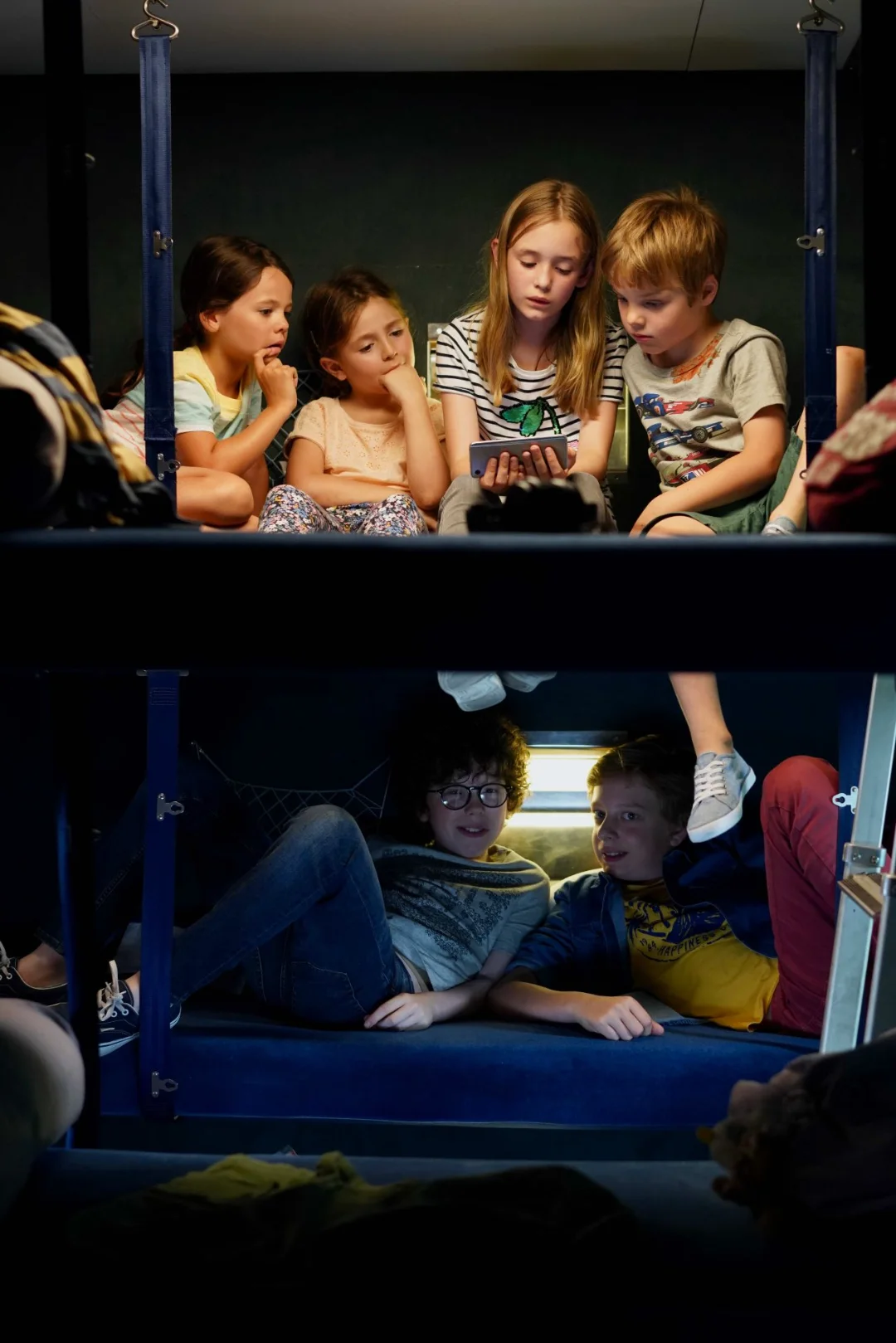 Des enfants allongés sur les couchettes d'un train de nuit.