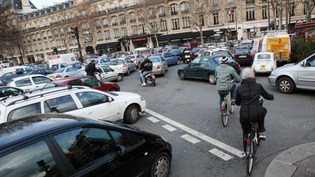 Embouteillage : un cycliste se faufile entre les voitures arrêtées d'un carrefour parisien.