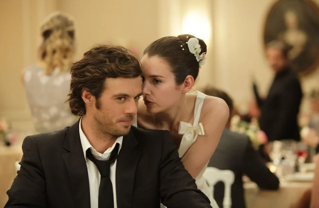 La mariée murmure à l'oreille d'un homme en costume sombre.