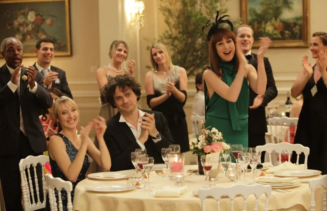 Les invités d'un mariage applaudissent debout autour d'une table dressée.